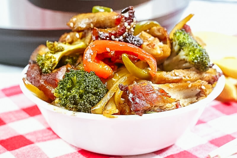 Close up of honey garlic chicken topped with broccoli and bell peppers.