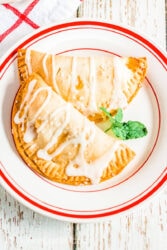 A white and red plate with two hand pies on it.