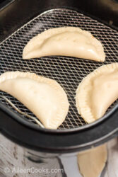 Three uncooked hand pies in an air fryer.