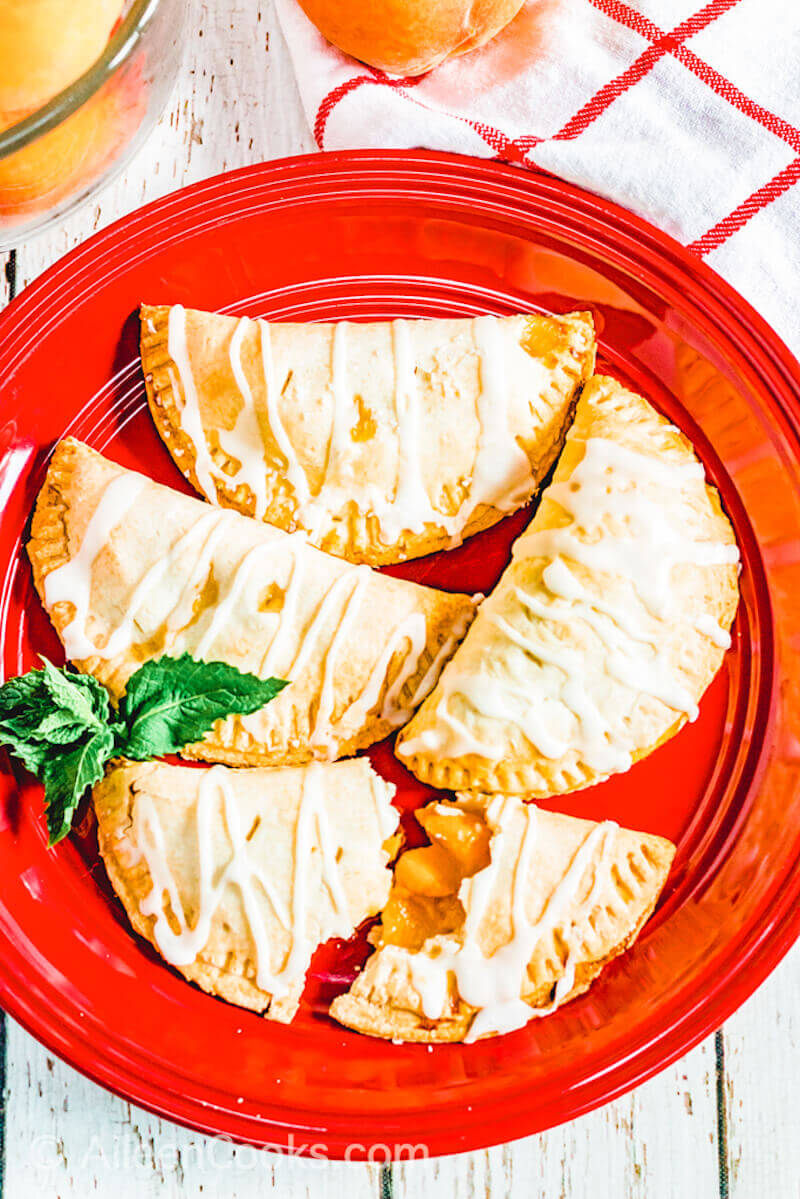 A red plate filled with peach hand pies.