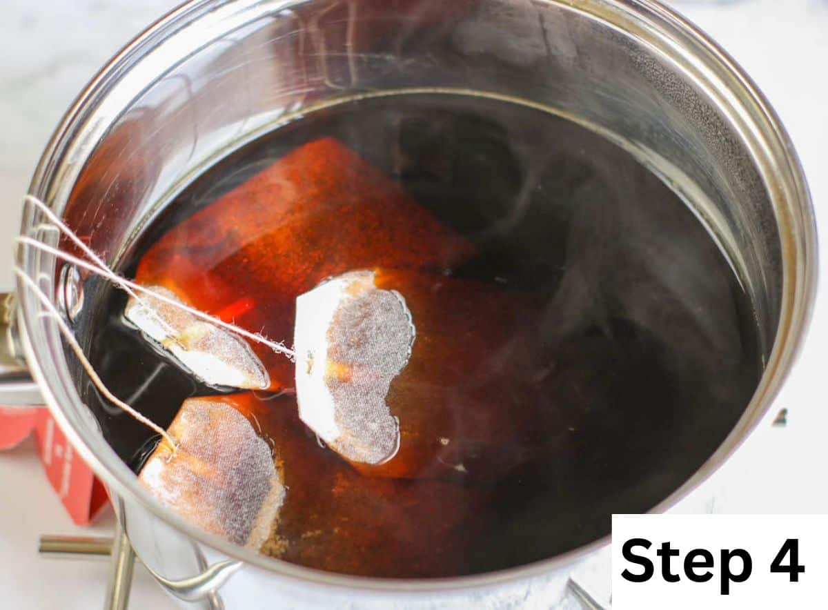 Three tea bags in a pot of boiling water.