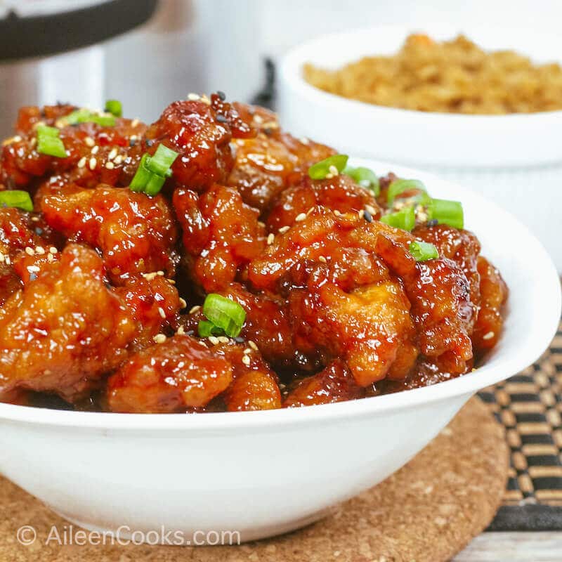 Side view of a white bowl piled high with general tso's chicken.