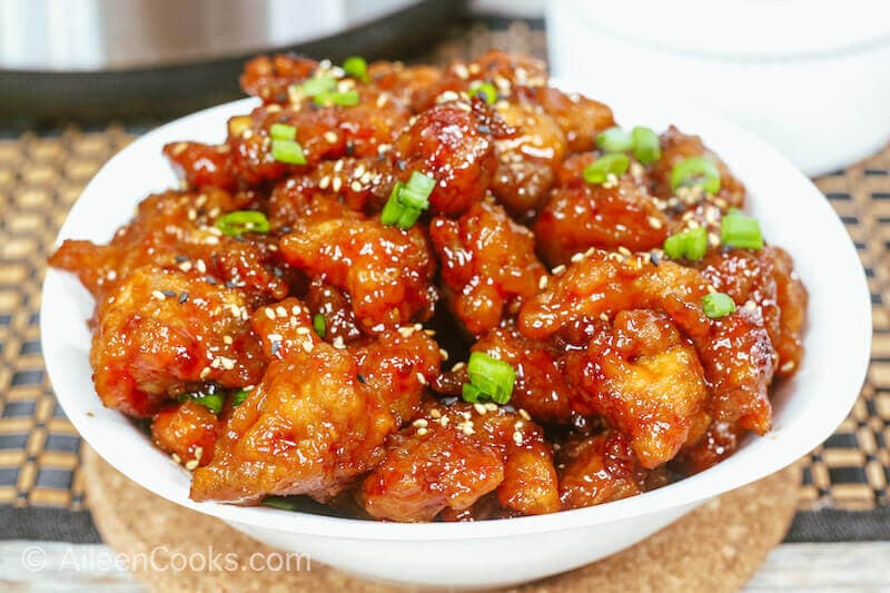 Close up of general tso chicken in a white bowl.