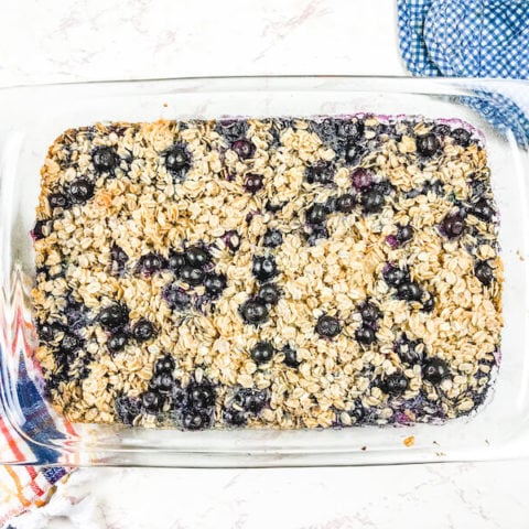 A glass baking dish filled with baked oatmeal and topped with blueberries.