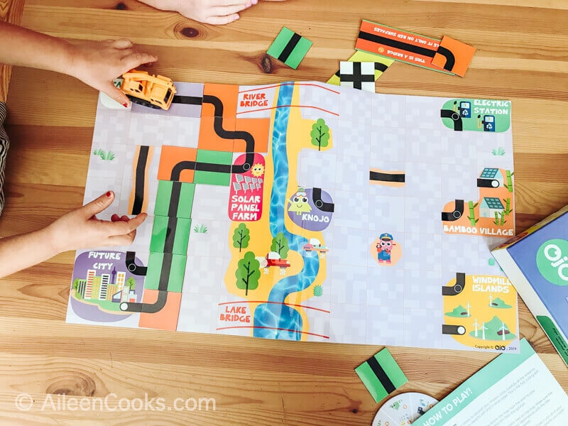 Overhead shot of Which Way? Coding board game and two sets of hands playing.