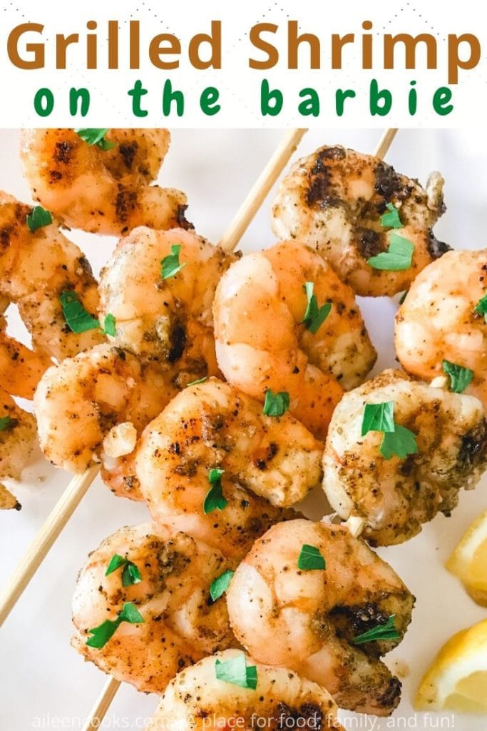 Close up of grilled shrimp topped with chopped parsley and the words "grilled shrimp on the barbie" in brown and green lettering