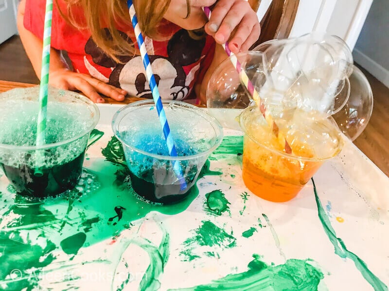 Three cups of colorful water with straws sticking out of them.