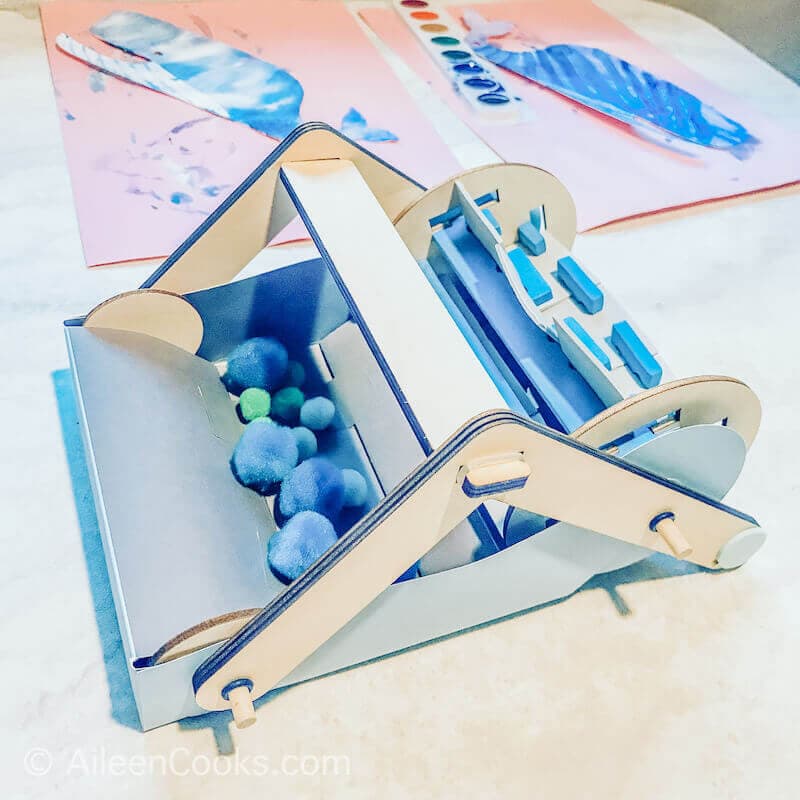 Overhead shot of a mechanical sweeper filled with blue Pom Poms.