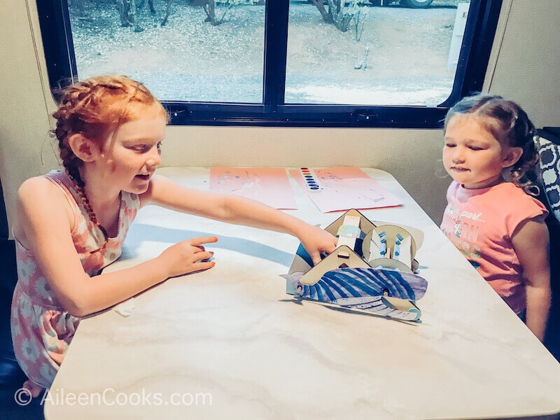 A little girl pushing her mechanical sweeper across a table.