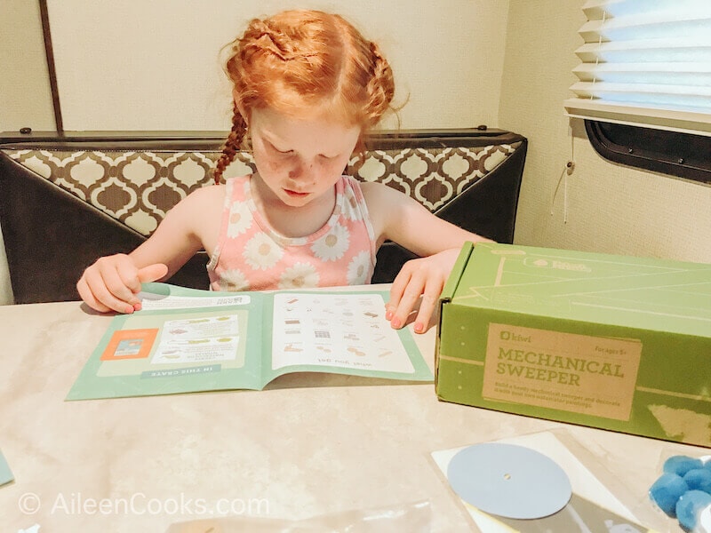 A little girl reading the instructions for kiwi crate.