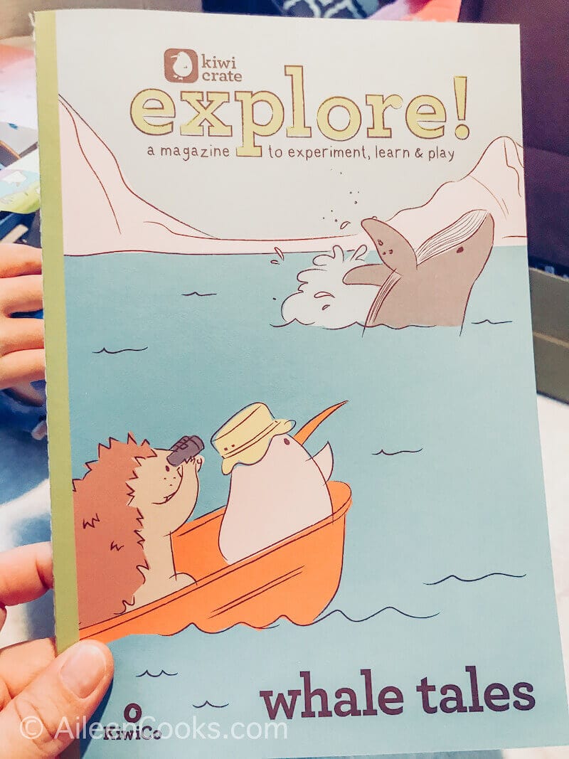 A hand holding the explore magazine from KiwiCo.