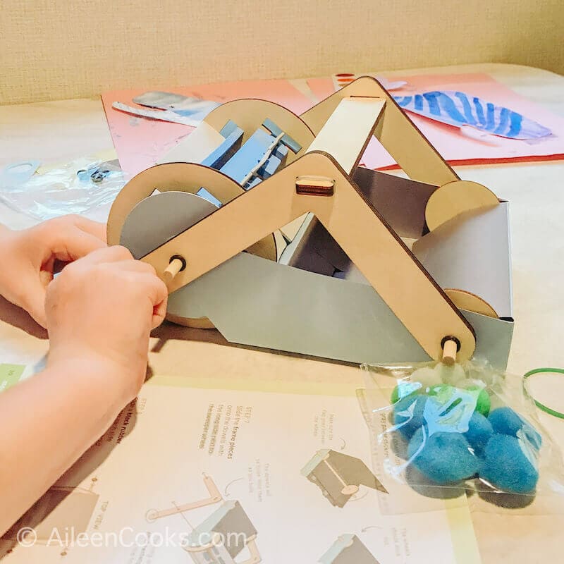 A child's hands building a mechanical sweeper.