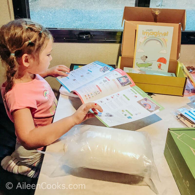 A little girl looking at the instruction booklet for her Koala Crate.