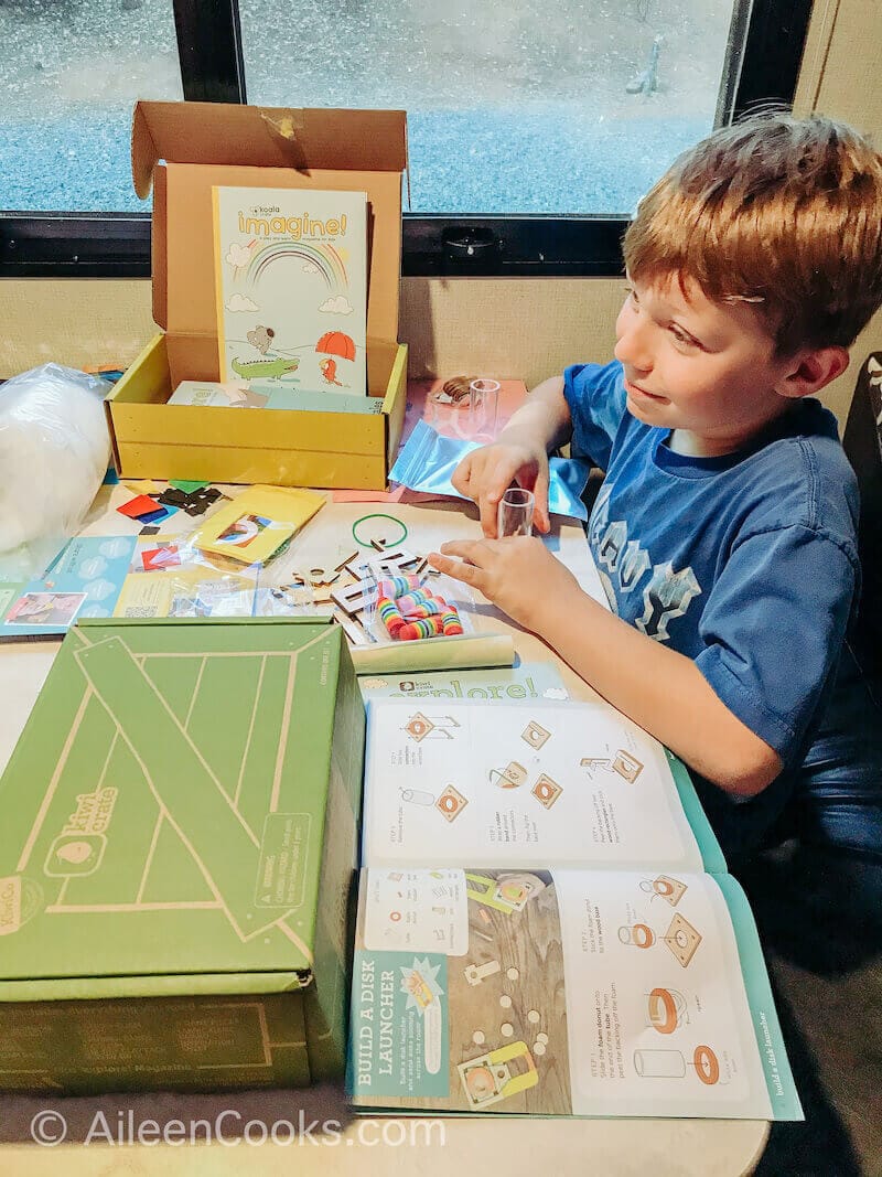 A boy building a disk launcher from kiwi crate.