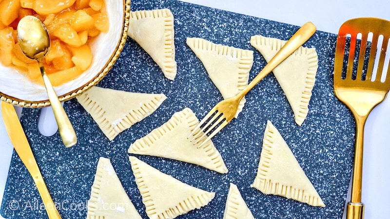Puff pastry folded into triangles and the edges being crimped by a fork.