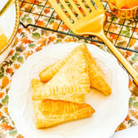 Three apple hand pies stacked up on a white plate.