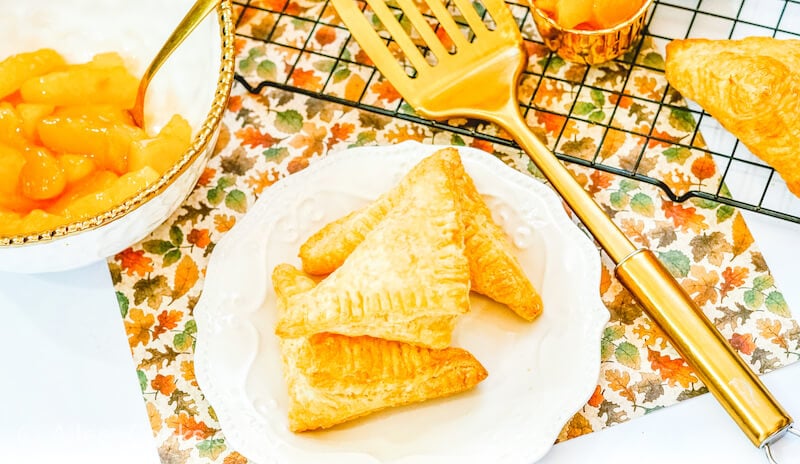 Three apple hand pies stacked up on a white plate.