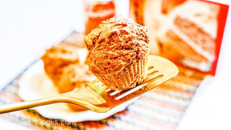 A pumpkin muffin held at an angle on a gold spatula.