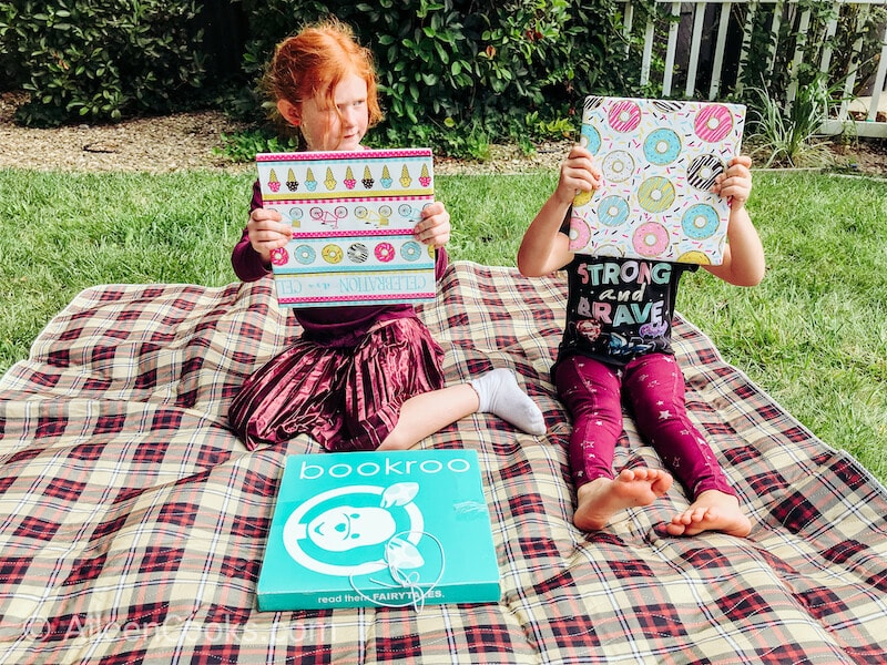 Two girls holding up gift wrapped books.