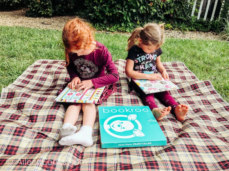 Two girls opening wrapped books.