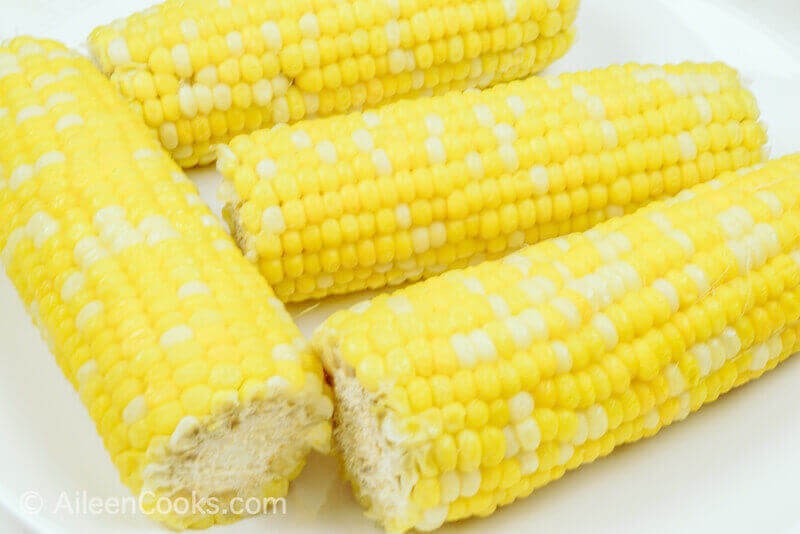 Close up of four ears of cooked corn.