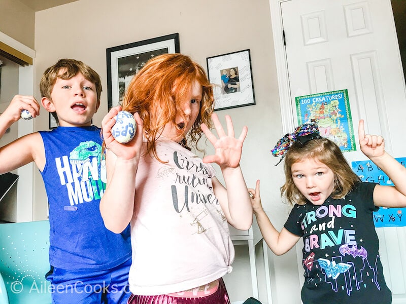 Three kids dancing and holding egg shakers.