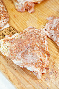 Raw chicken thighs rubbed with seasoning.