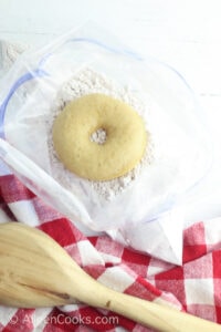 Donut inside of bag of powdered sugar.