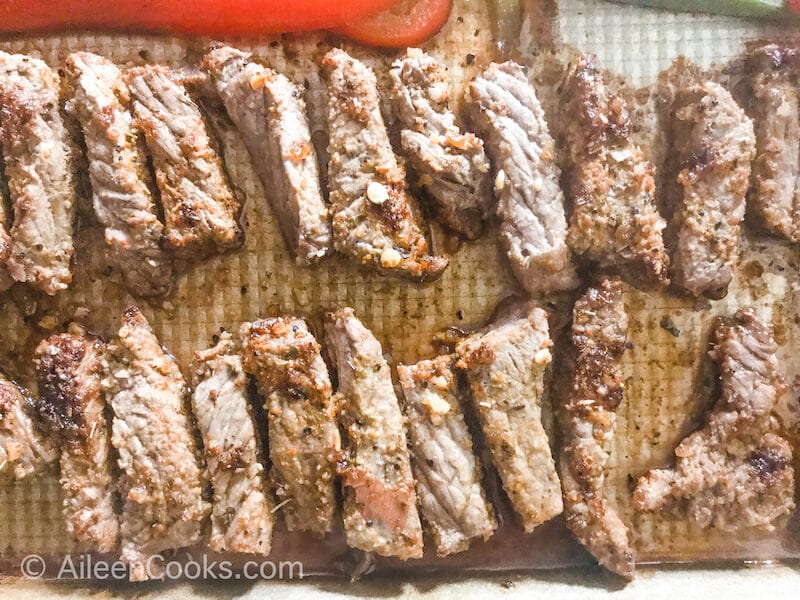 Sliced steak fajita meat on a cookie sheet.