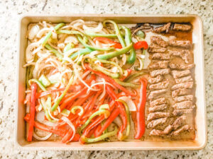 Cooked fajita meat and vegetables on a sheet pan.