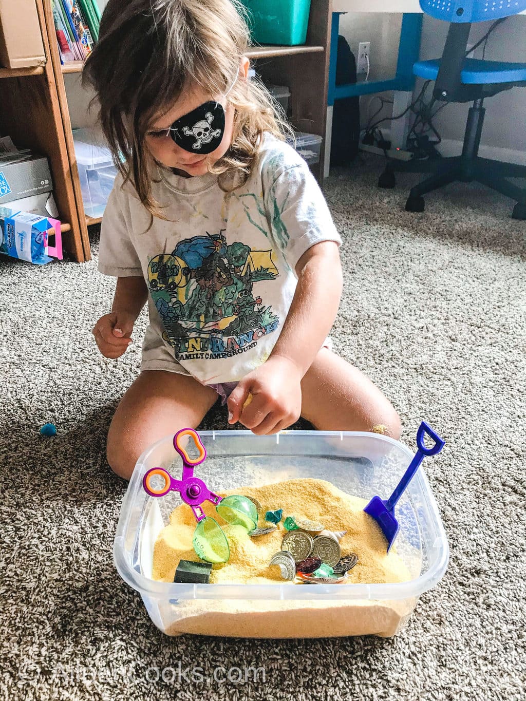 A little girl playing with a pirate themed sensory box and wearing a pirate eye patch.