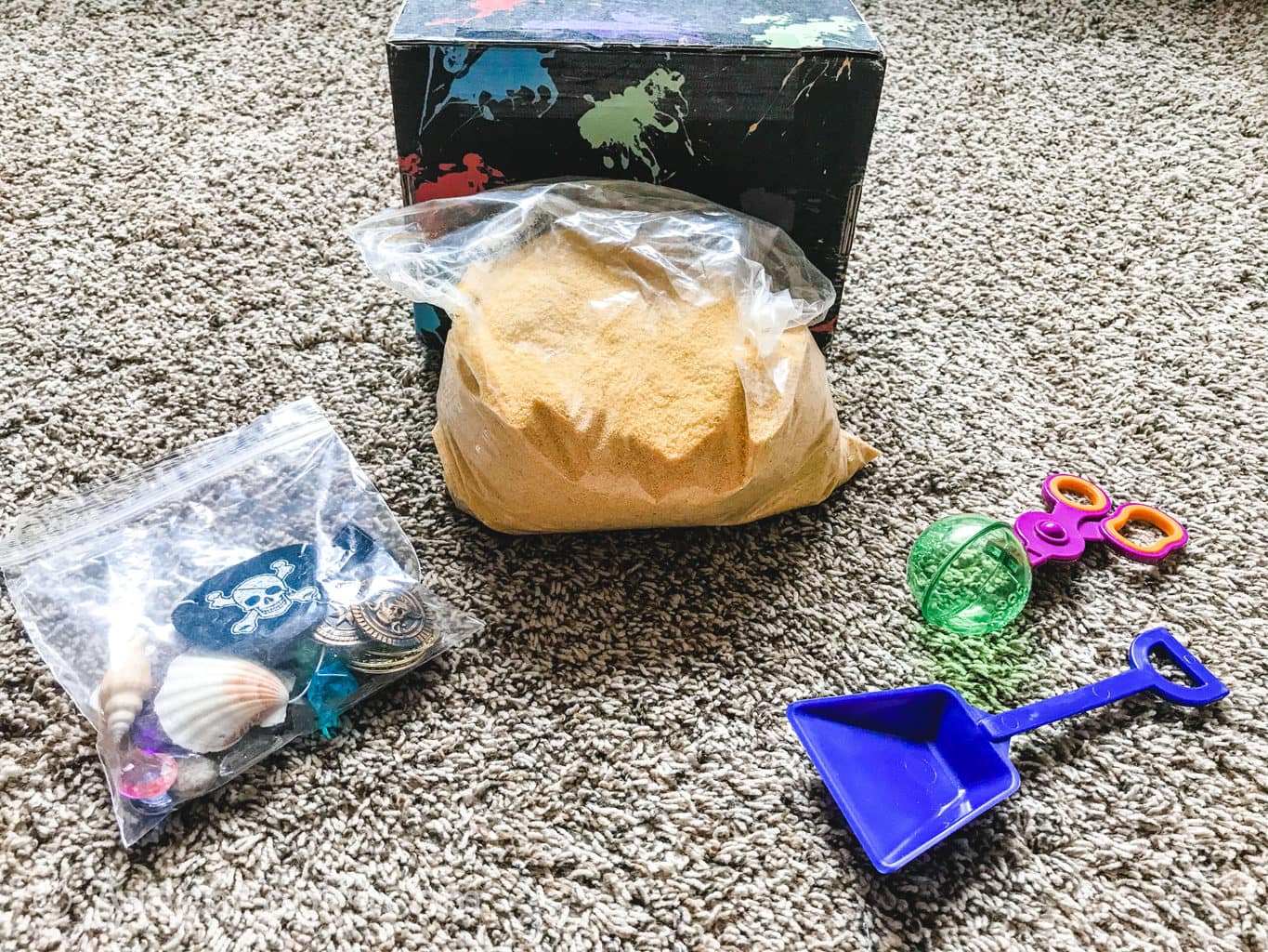 The contents of the messy play kids box on grey carpet.