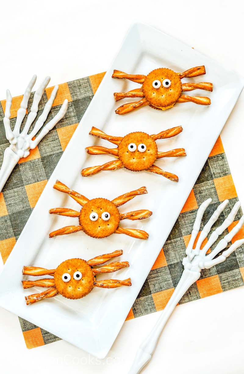 A white platter of four cracker sandwiches decorated as spiders.