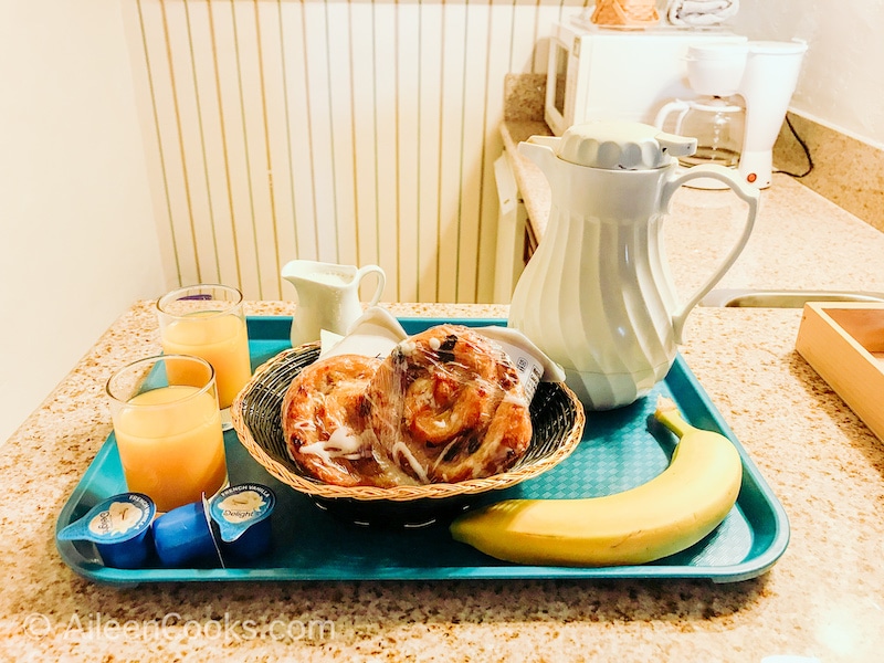 A blue tray filled with coffee, orange juice, banana, and pastries.
