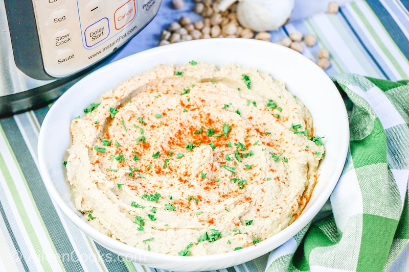 A bowl of hummus over a striped placemat.