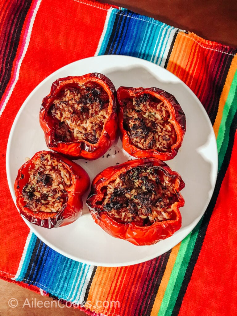 Four stuffed peppers on a white plate.