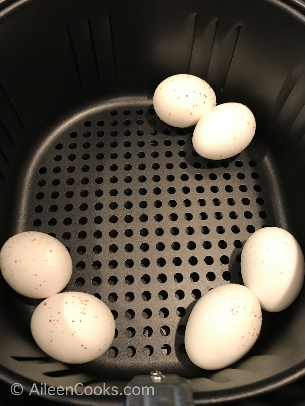 Six eggs inside of an air fryer.