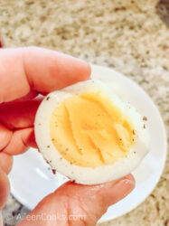 A hand holding a hard boiled egg cut in half.