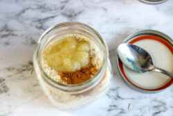 A mason jar filled with oats, milk, applessauce, and cinnamon.