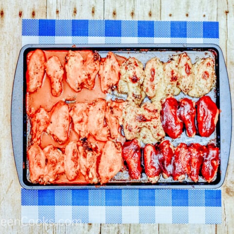 A sheet pan with three different kinds of baked chicken wings.