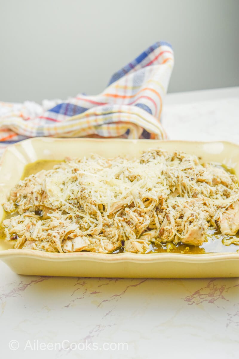 Side view of pesto chicken in a beige serving dish.