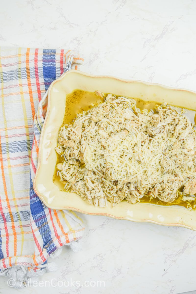 Overhead shot of crockpot pesto chicken topped with parmesan cheese.