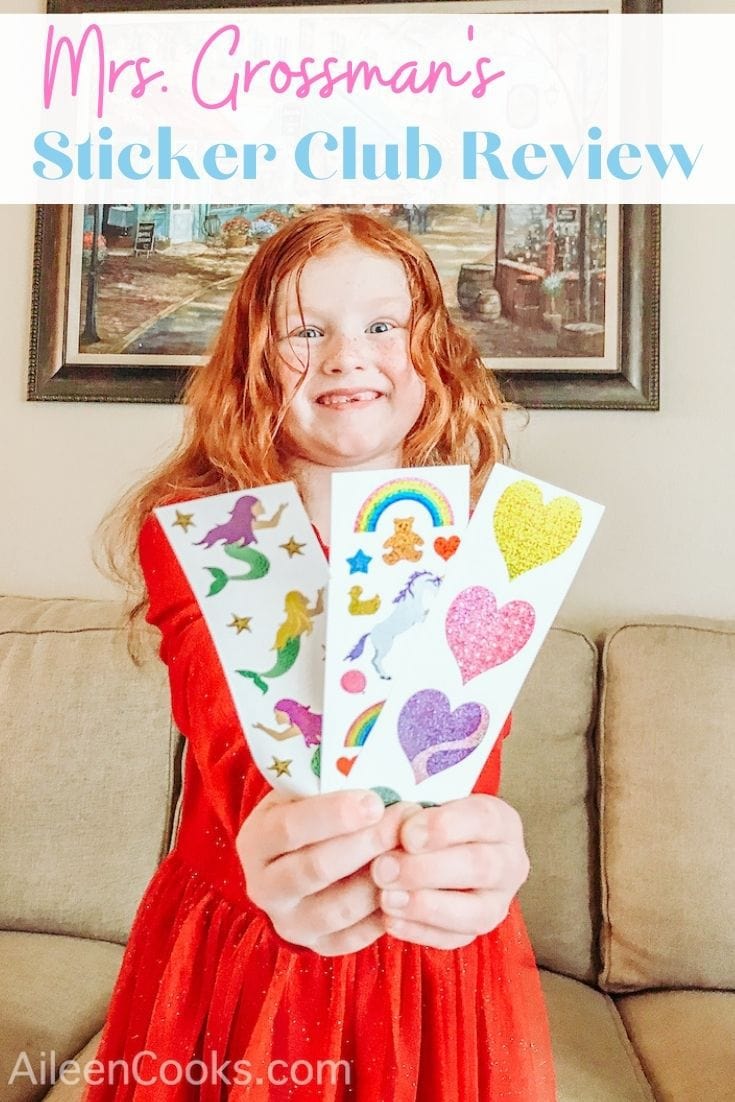 A little girl holding up three sheets of stickers with the words "Mrs. Grossman's Sticker Club Review" in pink and blue lettering.