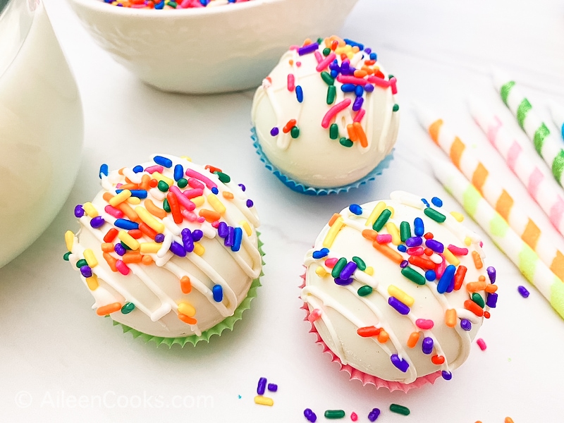 Three white chocolate bombs sitting on colorful muffin cups.