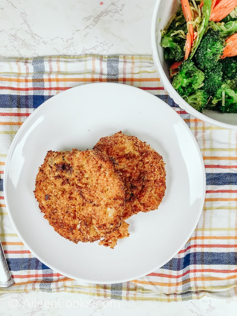 Overhead shot of pork chops on a plate and mixed vegetables in a bowl.