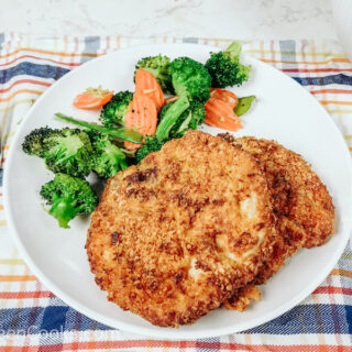 A white plate of crispy air fryer pork chops and mixed vegetables.