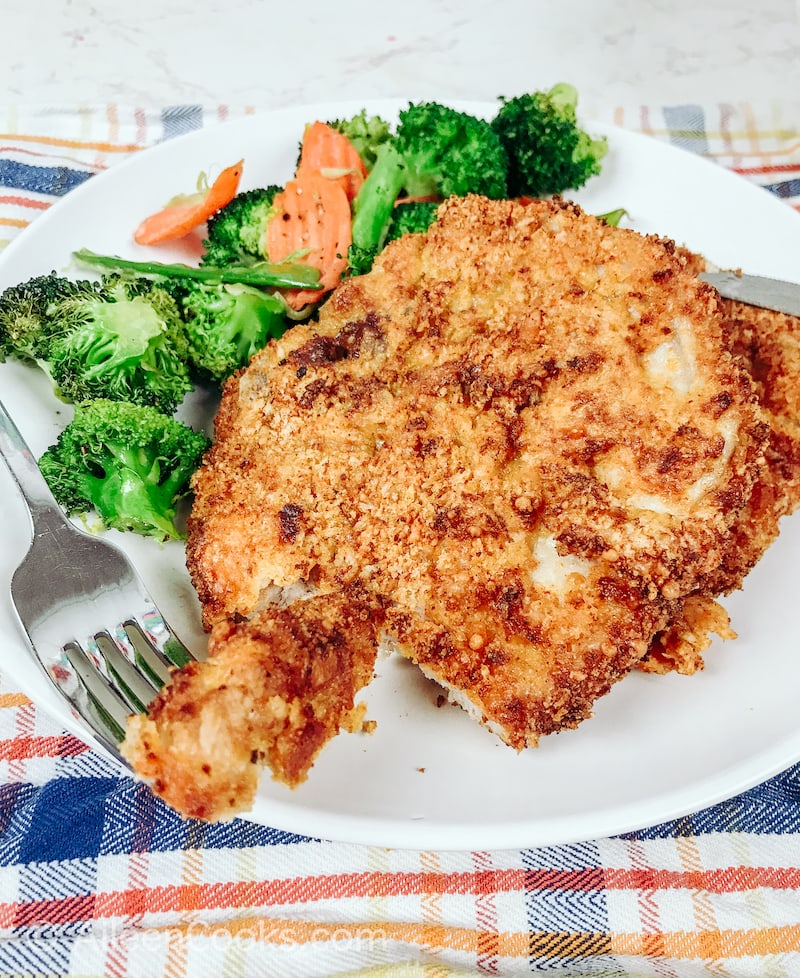 A bite of pork chops resting on a white plate.