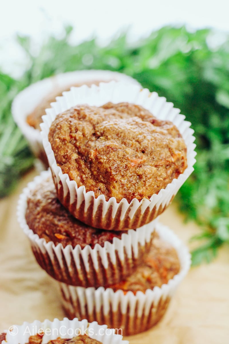 An arrangement of six carrot muffins in white paper muffin cups.