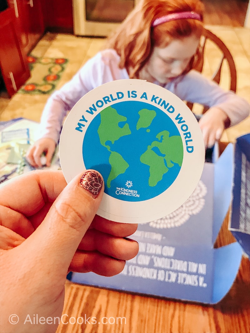 A hand holding up a sticker of Earth.