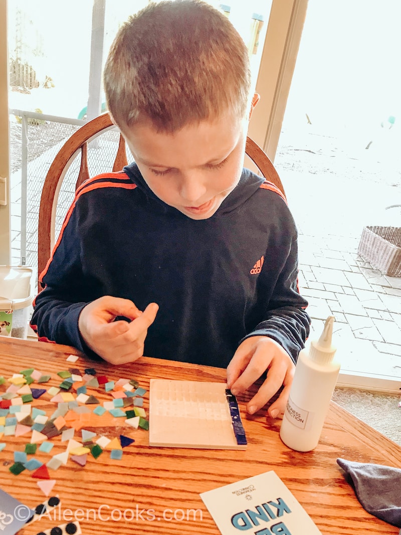 A boy making a mosaic coaster.